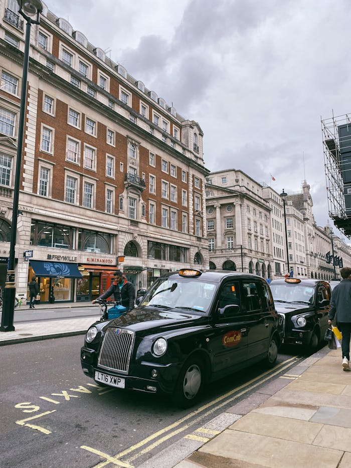 Classic black taxi cabs parked along a bustling street in London, showcasing iconic city life.
